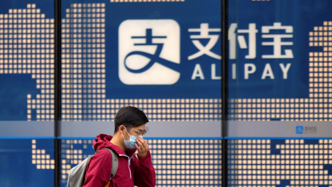 Un hombre pasa por delante de un cartel del sistea de pago electrónico Alipay, de Ant Group, en un edificio en Shanghai. EFE/EPA/ALEX PLAVEVSKI