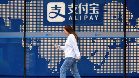 Una mujer pasa junto al logo del sistema de pago electrónico Alipay, de Ant Group, en un edificio en Shanghai. EFE/EPA/ALEX PLAVEVSKI