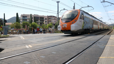 10/09/2024 - Un tren de Rodalies circula per Montcada i Reixac al costat d'un pas a nivell.