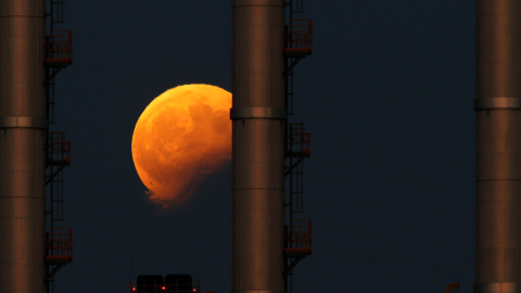 Imagen del eclipse lunar detrás de las chimeneas de una central eléctrica en Delimara (Malta). Darrin Zammit / REUTERS