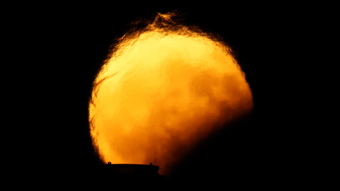 Imagen del eclipse lunar detrás de las chimeneas de una central eléctrica en Delimara (Malta). Darrin Zammit / REUTERS