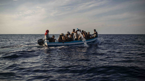 Un grupo de 17 jóvenes tunecinos achican agua de la patera en la que navegan hacia Lampedusa (Italia) escoltadas por el buque Astral de Open Arms, este miércoles.