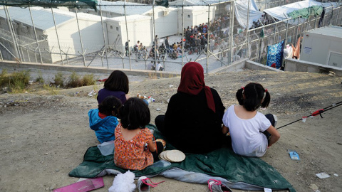 Una mujer observa con sus hijos el campamento de Moria.