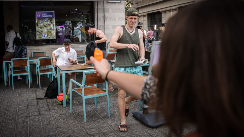 Una dona dispara una pistola d'aigua contra uns turistes en un restaurant de menjar ràpid