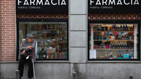 Un hombre mayor sentado en el escaparate de una farmacia en Madrid. REUTERS/Juan Medina