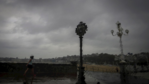 Una mujer camina bajo la lluvia en San Sebastián.