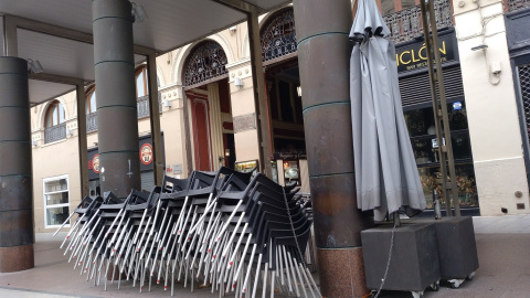 Las sillas y mesas de un bar cerrado cogen polvo a la espera de tiempos más prósperos en una céntrica plaza de Zaragoza.