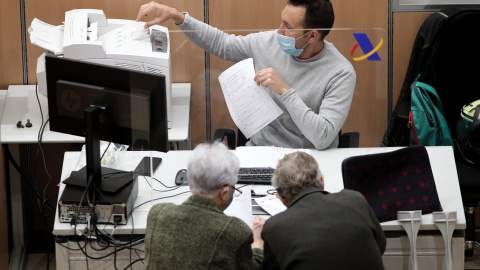 Un empleado de la Agencia Tributaria atiende a dos personas para la tramitación de su declaración del IRPF, en la Campaña de la Renta. E.P./Eduardo Parra