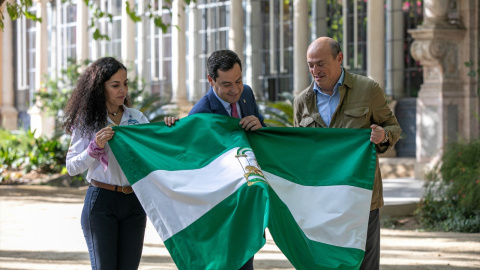 El presidente de la Junta de Andalucía, Juanma Moreno (c) entrega una bandera andaluza al creador del Reto Pelayo Vida, Eric Frattini (d) y a la expedicionaria almeriense Felisa Requena (i) antes de despedir a la expedición de la nueva edición.