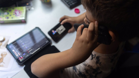 Un niño usa el teléfono móvil y una tablet. E.P./Eduardo Parra Europa Press