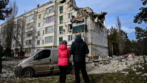 02/12/2022 Dos personas residentes en la zona observan los daños en un bloque de viviendas bombardeado en la ciudad ucraniana de Kluhyno-Bashkyrivka (Járkov)