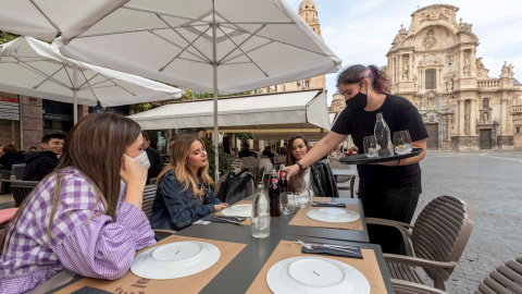 Una camarera sirve la bebida en la mesa de la terraza de un restaurante este miércoles en la Plaza Cardenal Belluga de Murcia.