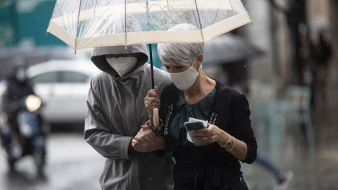 Dos personas se protegen de la lluvia bajo un paraguas, en Sevilla.