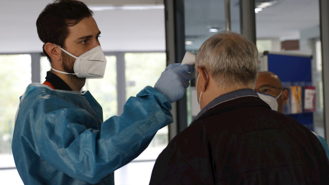 Personal sanitario del SERMAS toma la temperatura a una persona en la entrada de una residencia de mayores.