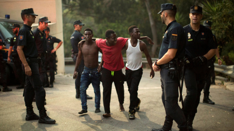 Agentes de la Guardia Civil junto a tres de los migrantes tras cruzar la frontera. REUTERS