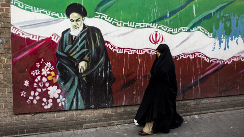 Una mujer junto a un mural con la bandera iraní y el ayatolá Ruholá Jomeini en Teherán (Irán). Imagen de Archivo.