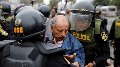 Un manifestante herido entre los agentes de policía apostados fuera de la Prefectura de Lima, mientras declaraba el presidente destituido Pedro Castillo. REUTERS/Alessandro Cinque