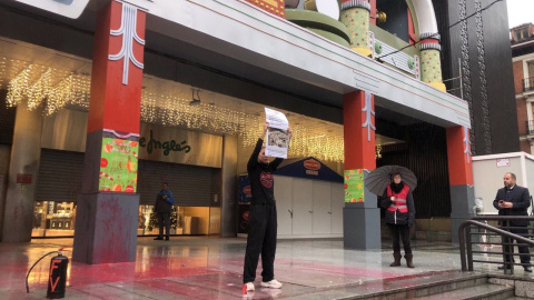 Una activista sostiene una pancarta tras rociar con pintura parte del escenario navideño infantil de Cortylandia.