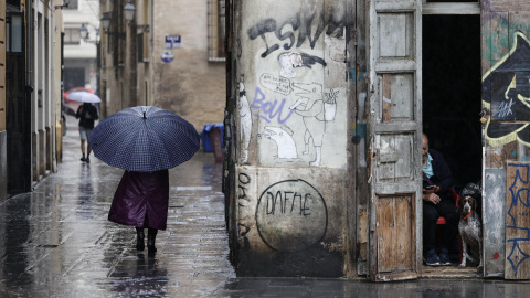 Una persona camina bajo la lluvia por las calles del centro histórico de València.