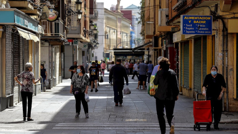 Ciudadanos con mascarillas paseando por una calle de València. /EFE