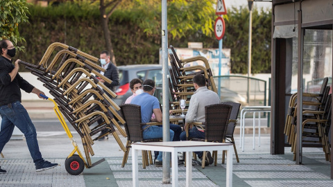 Camareros de un bar de Mairena del Aljarafe(Sevilla) recogen el mobiliario para proceder al cierre antes de las seis de la tarde