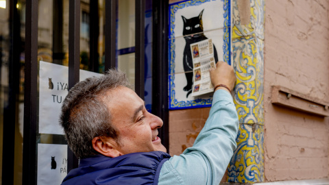 Una persona pone el décimo recién comprado en el azulejo que representa a el gato negro en la administración de loterías ‘El Gato Negro’ en Sevilla- 07/12/2022