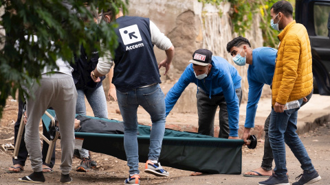 Unos inmigrantes y personal de la ONG Accem, que gestiona el campamento humanitario de Las Raíces, trasladan a uno de los heridos en los altercados.