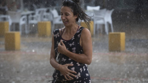 Una mujer corre bajo la lluvia en la Alameda de Hércules (Sevilla) a 14 de septiembre de 2021.