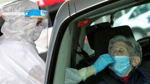 Una sanitaria protegida con EPI toma una muestra para una prueba PCR frente al hospital de Gandía.