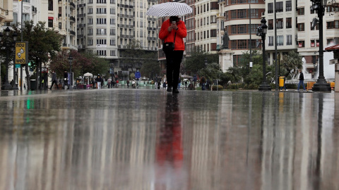 09/04/2021. Una persona se protege de la lluvia con un paraguas este viernes, en València. - EFE