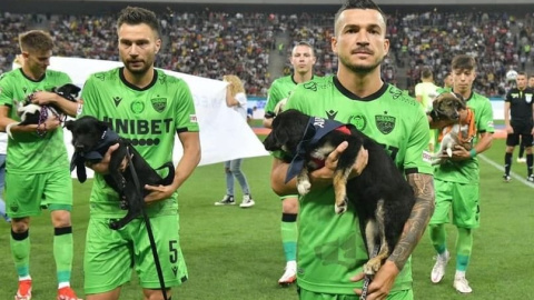 Los jugadores del Dínamo de Bucarest sosteniendo perros en adopción antes del partido.