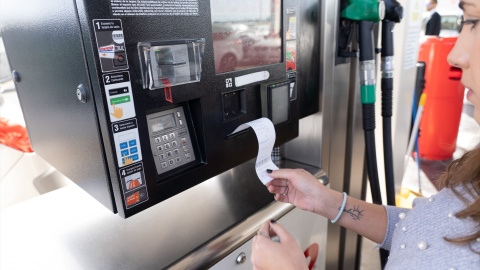 Cliente recoge un recibo en la gasolinera.