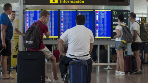 Varios viajeros consultan lo vuelos en los monitores del Aeropuerto de Barcelona-El Prat. EFE/Quique García