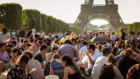 Numerosos grupos de turistas hacen un picnic frente a la Torre Eiffel /Architecture and Design