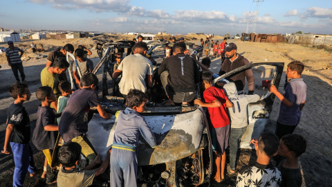 30/09/2024 | Niños palestinos se reúnen alrededor de un automóvil destruido por aviones de combate israelíes, en Khan Yunis (Franja de Gaza).