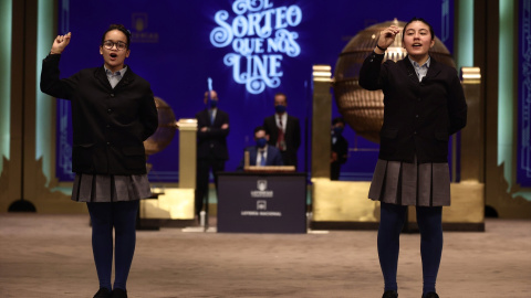 Paula Figuereo y Yanisse Alexandra, dos de las niñas de la residencia de San Ildefonso, posan minutos después de cantar el primer premio 86.148, durante la celebración del Sorteo Extraordinario de la Lotería de Navidad 2021 en el Teatro Real de Madrid