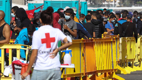 Una voluntaria de Cruz Roja junto a varios inmigrantes este jueves en el muelle de Arguineguín.