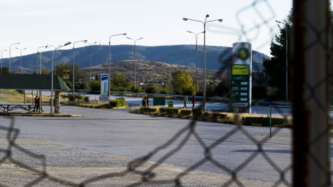 En primer plano, una valla rota. Al fondo, una gasolinera en Evzoni. - Cedida