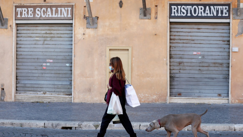 Una mujer pasea frente a un restaurante cerrado en Roma, Italia