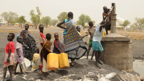 Mujeres y niños recogen agua de un pozo en un campamento de Sudán del Sur.REUTERS / Jok Solomun