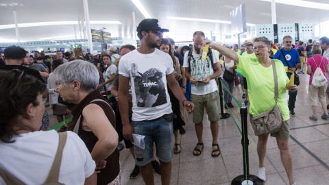 Miembros de la Asamblea Nacional de Cataluña (ANC) repartiendo folletos en el Aeropuerto de Barcelona-El Prat culpando al Estado de las colas que se han formado en las dos últimas semanas en los controles de seguridad del aeropuerto. EFE/Quique García