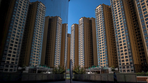 Una mujer camina cerca de bloques de edificios de apartamentos levantados por la inmobiliaria Evergrande, en Pekín. EFE/ROMAN PILIPEY