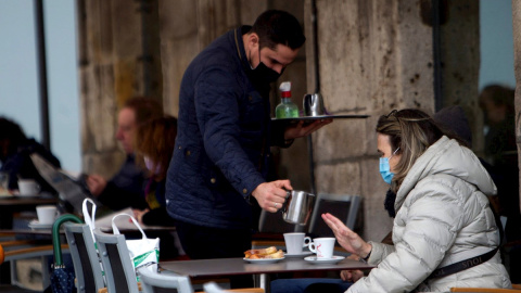 Un camarero sirve un café en la terraza de un bar en Vigo.