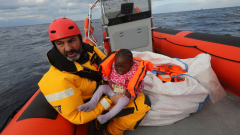 Un voluntario de Proactiva Open Arms rescata a un menor que iba junto a cientos de eprsonas en una bote hinchable en el Mediterráneo.- Una embarcación cargada de personas flota a la deriva en el Mediterráneo.- REUTERS/Yannis Behrakis