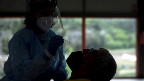 Una trabajadora sanitaria realiza una prueba PCR a un hombre, durante el cribado realizado este lunes a la población de Sobradelo (Carballeda de Valdeorras).