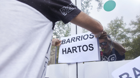 Un vecino coloca un cartel en la puerta de una oficina durante una protesta del colectivo Barrios Hartos. Imagen de archivo.