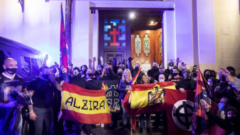 Varios ultraderechistas sostienen una bandera franquista en el acceso a la Iglesia de Benimaclet, el pasado 12 de octubre.