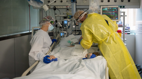 Dos sanitaris visitant un pacient de Covid a l'UCI de l'Hospital Clínic protegits amb EPI.