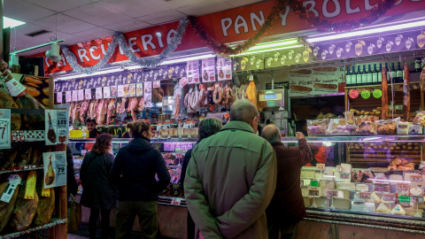 Varias personas esperan a ser atendidas en un puesto de productos alimentarios.