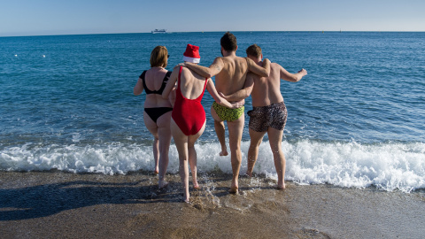 Unos jóvenes se bañan en la playa de la Barceloneta, a 25 de diciembre de 2022, en Barcelona.